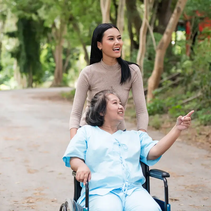 Giovane donna accompagna una signora in sedia a rotelle